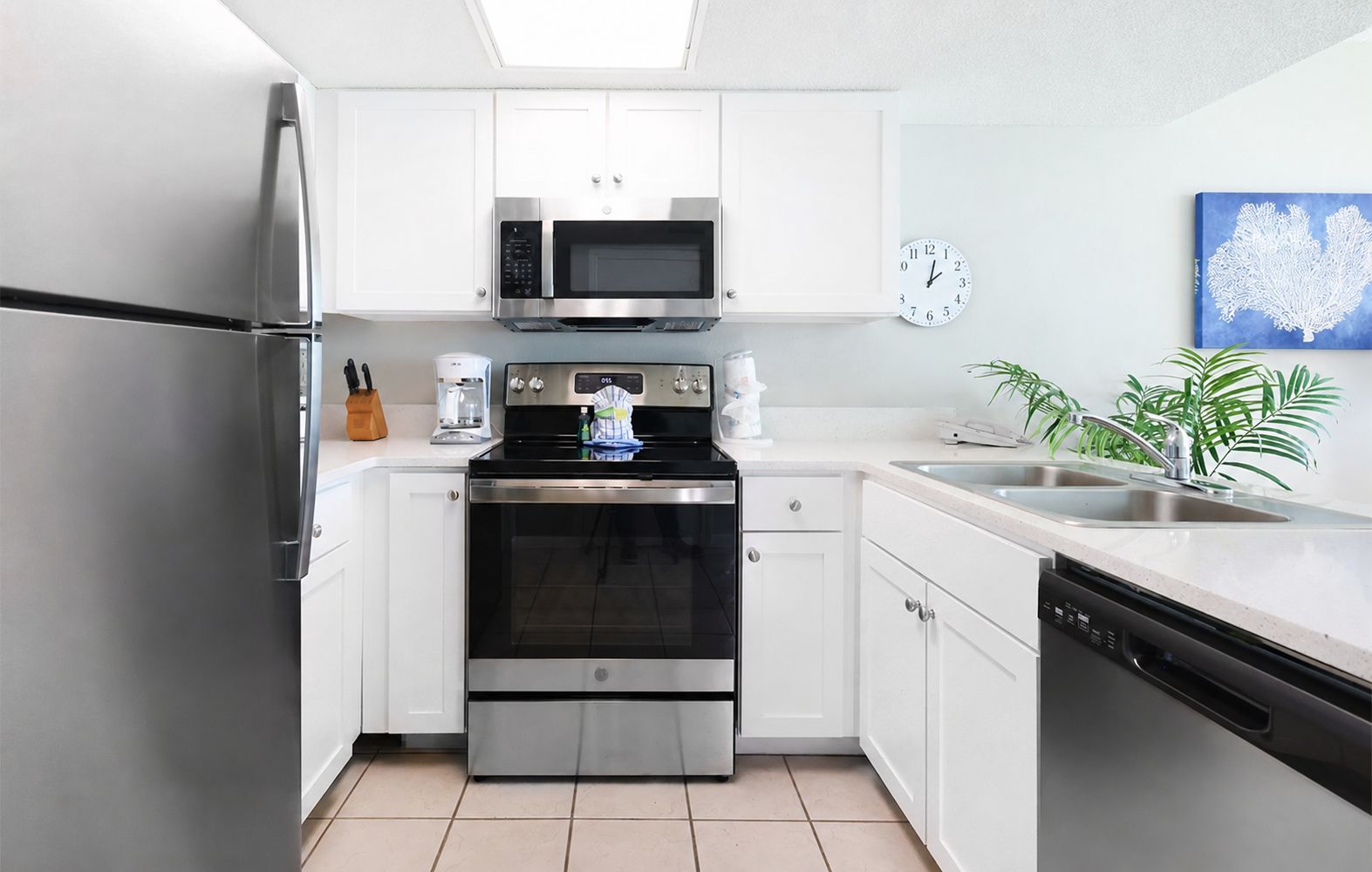 A modern kitchen with stainless steel appliances, white cabinetry, a built-in oven, a microwave, and a sink.