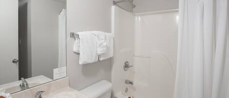 A bathroom with a sink, mirror, toilet, and shower.