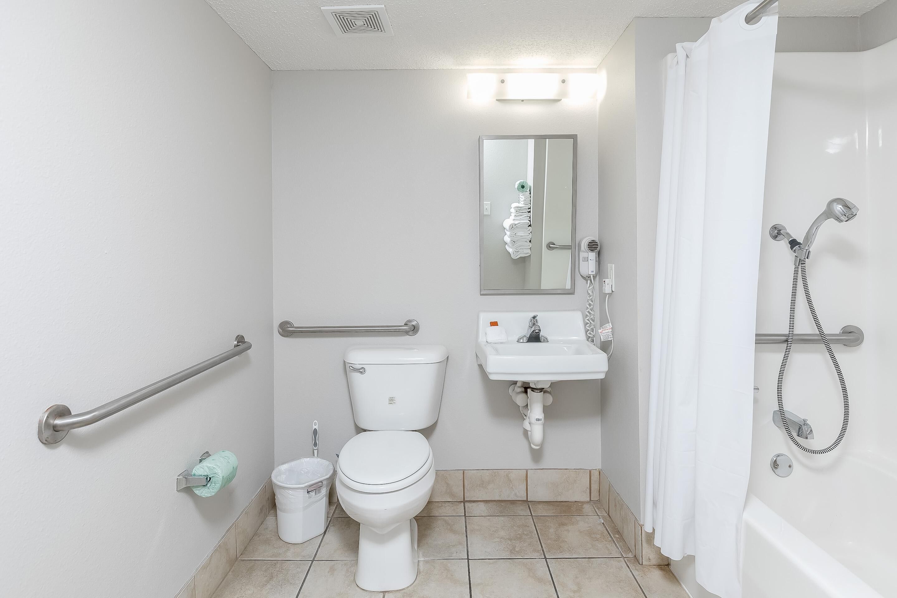 Et badeværelse med toilet, vask og bruser.