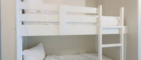 Una cama litera con ropa de cama blanca y una escalera.