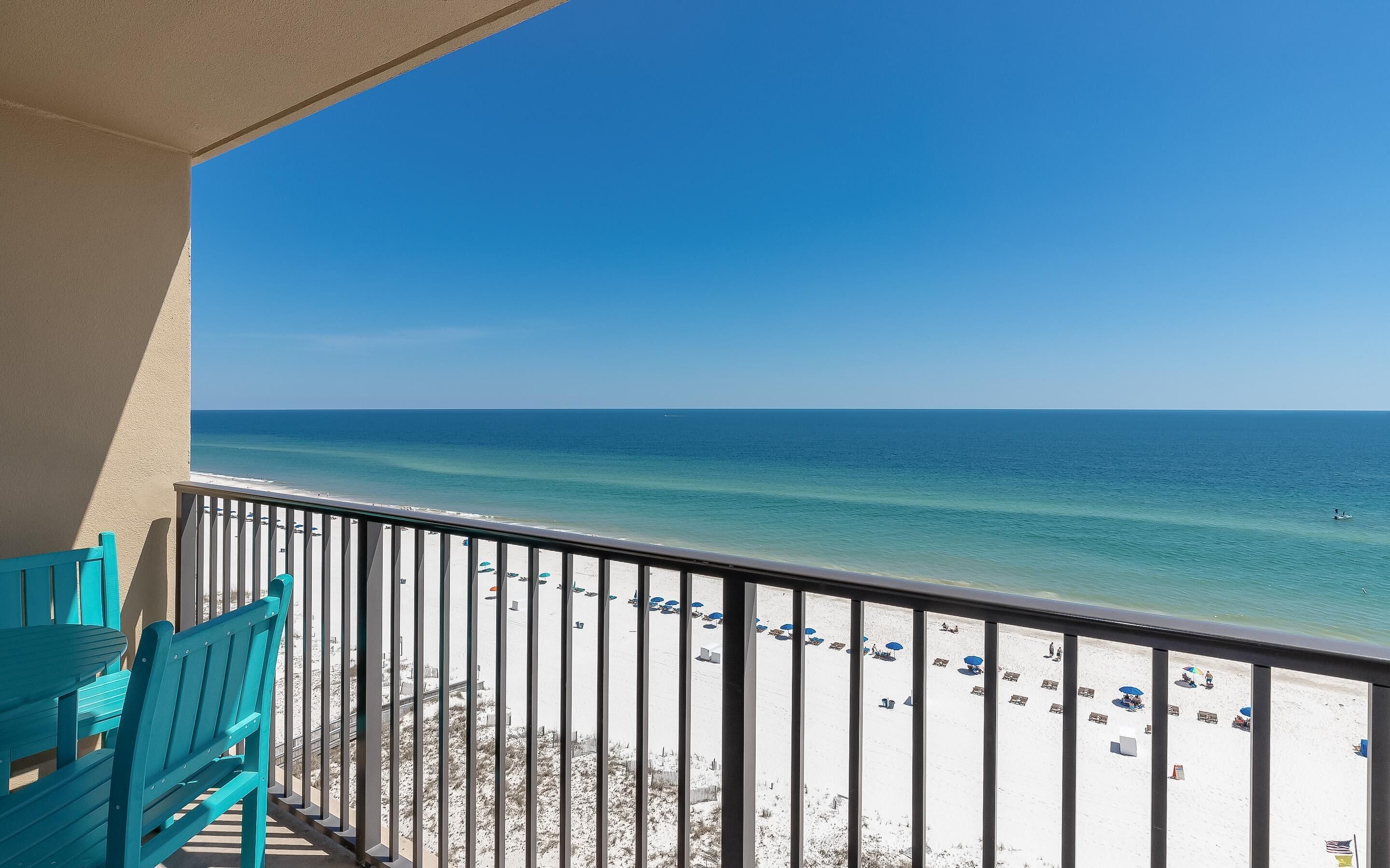 A balcony with a view of a beach with umbrellas and sun loungers.
