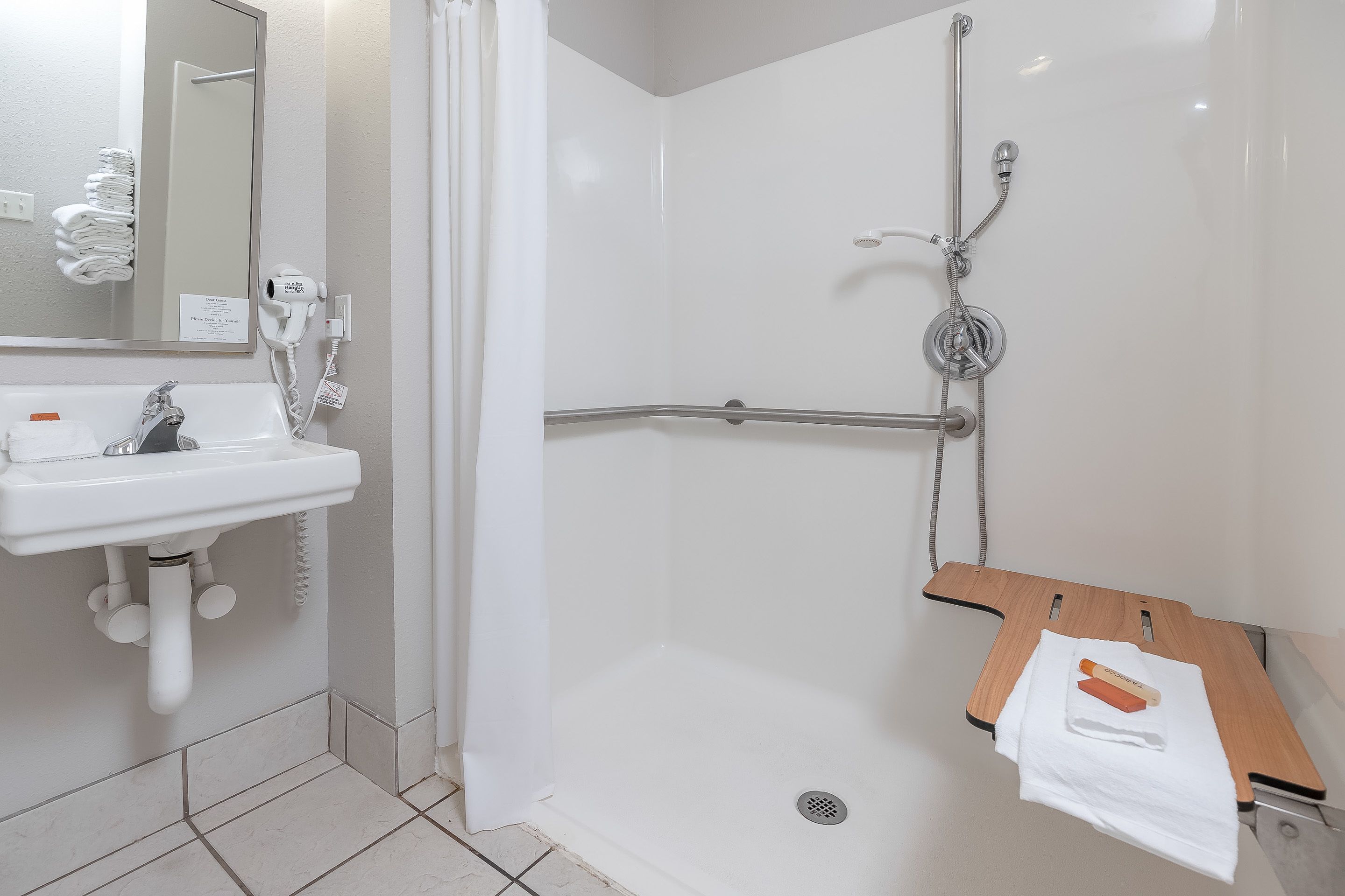 A bathroom with a white sink, mirror, and shower.