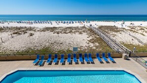 Ein Poolbereich mit blauen Liegestühlen und Blick auf den Strand.