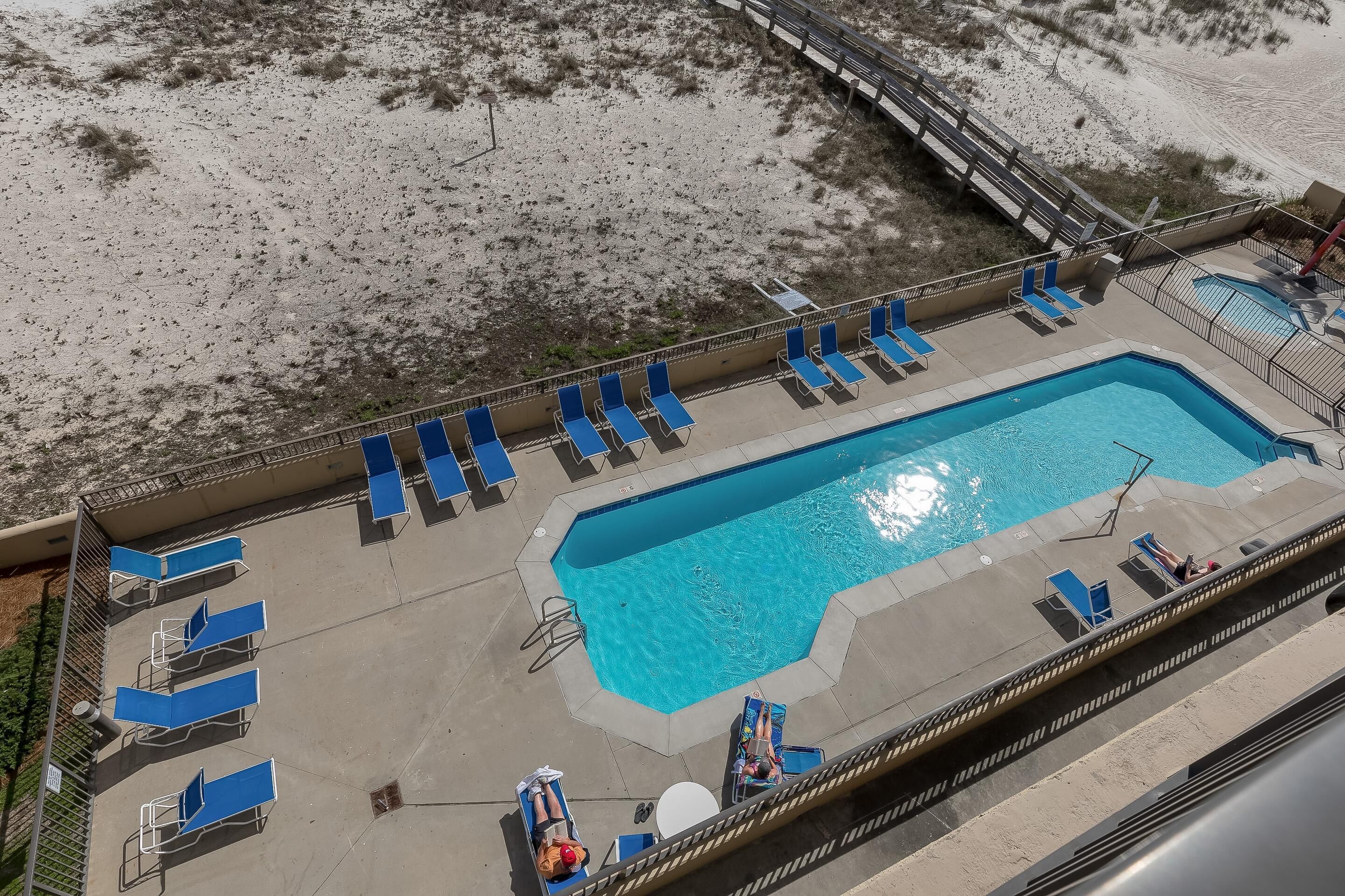 Vue aérienne d’une piscine avec des chaises longues bleues et une terrasse en bois.