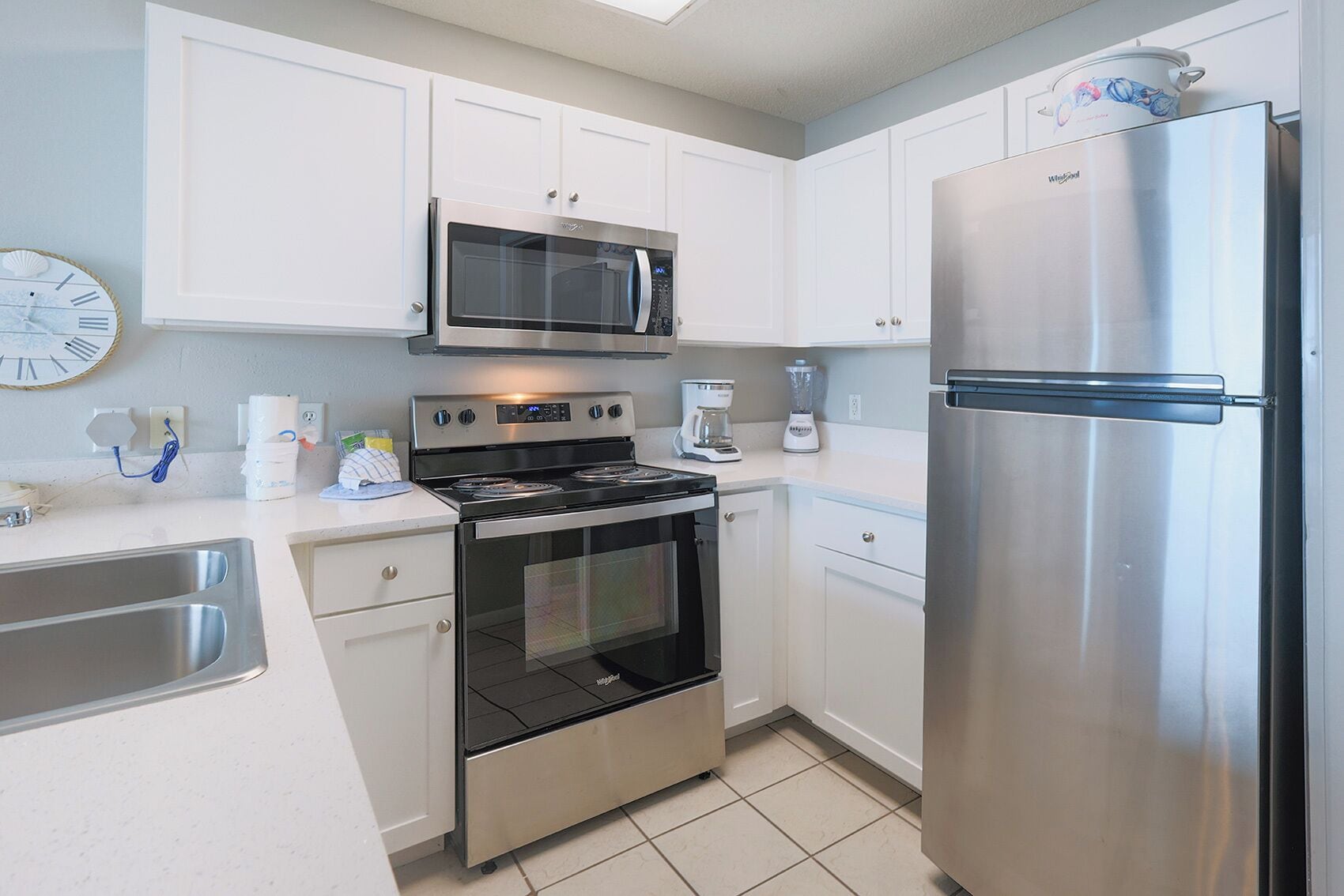 A modern kitchen with white cabinets, stainless steel appliances including a microwave, oven, and refrigerator, and a coffee maker on the counter.