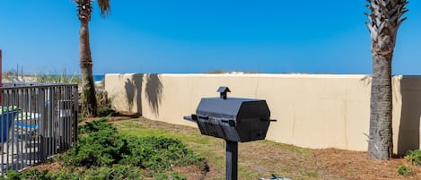 A barbecue grill in a landscaped outdoor area with a view of the ocean.