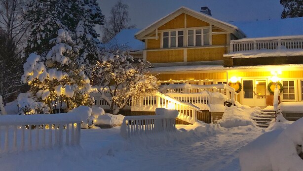 Een tweelaags huis met een voorerf bedekt met sneeuw en een houten omheining.