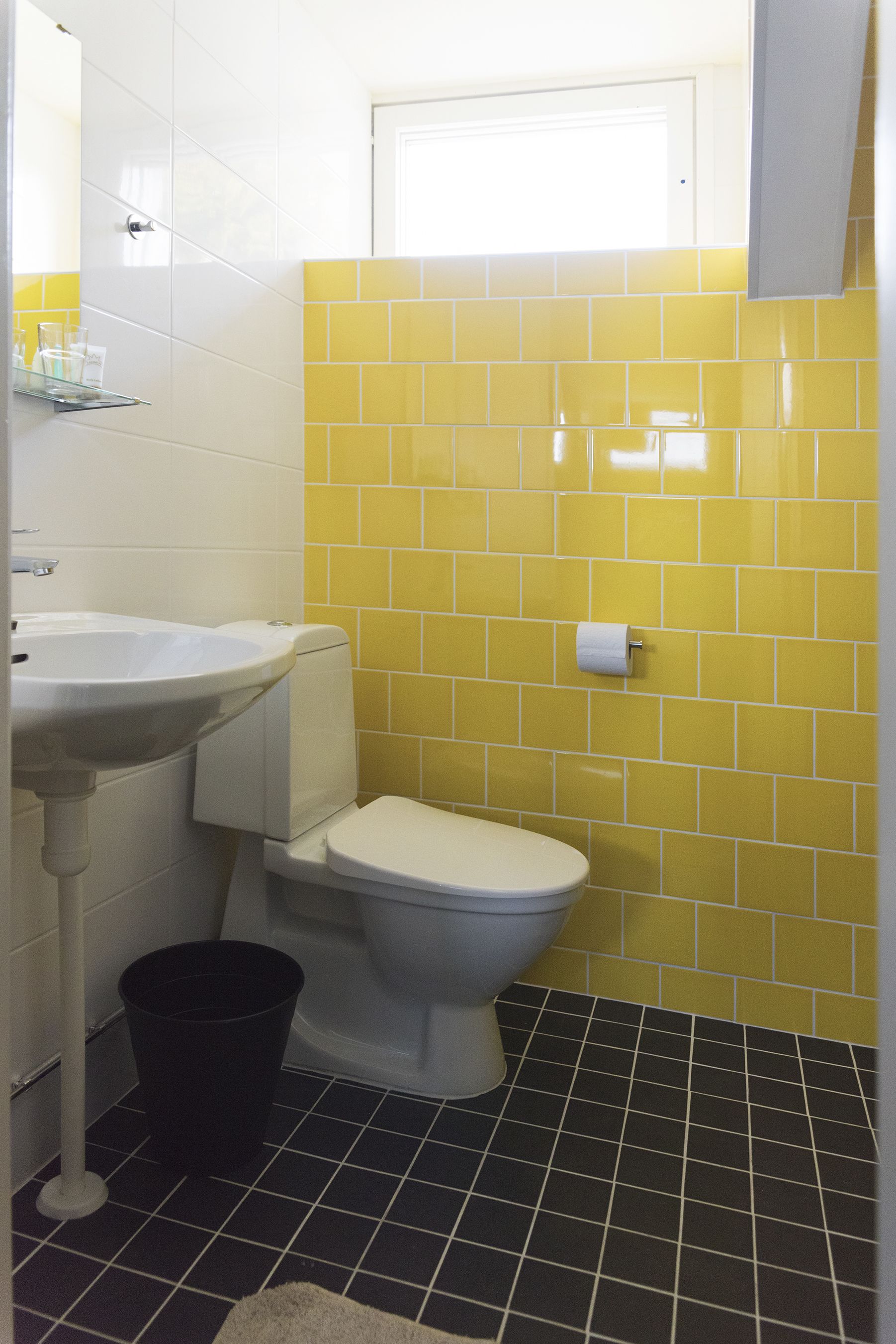 A bathroom with a white sink, a toilet, and yellow-tiled walls.