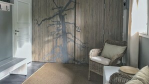 Een kamer met een geweven wandpaneel, een rieten stoel, een bank en een hanglamp.