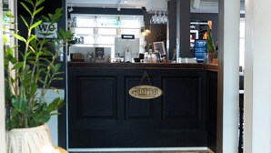 Een receptie met een donker aanmeldingsschrijntje, een bordje met daarop 'RECEPTION' en een balie met diverse spullen.