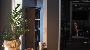 Een witte console tafel met een spiegel, een potplant, een lijst met foto en een klein mandje.