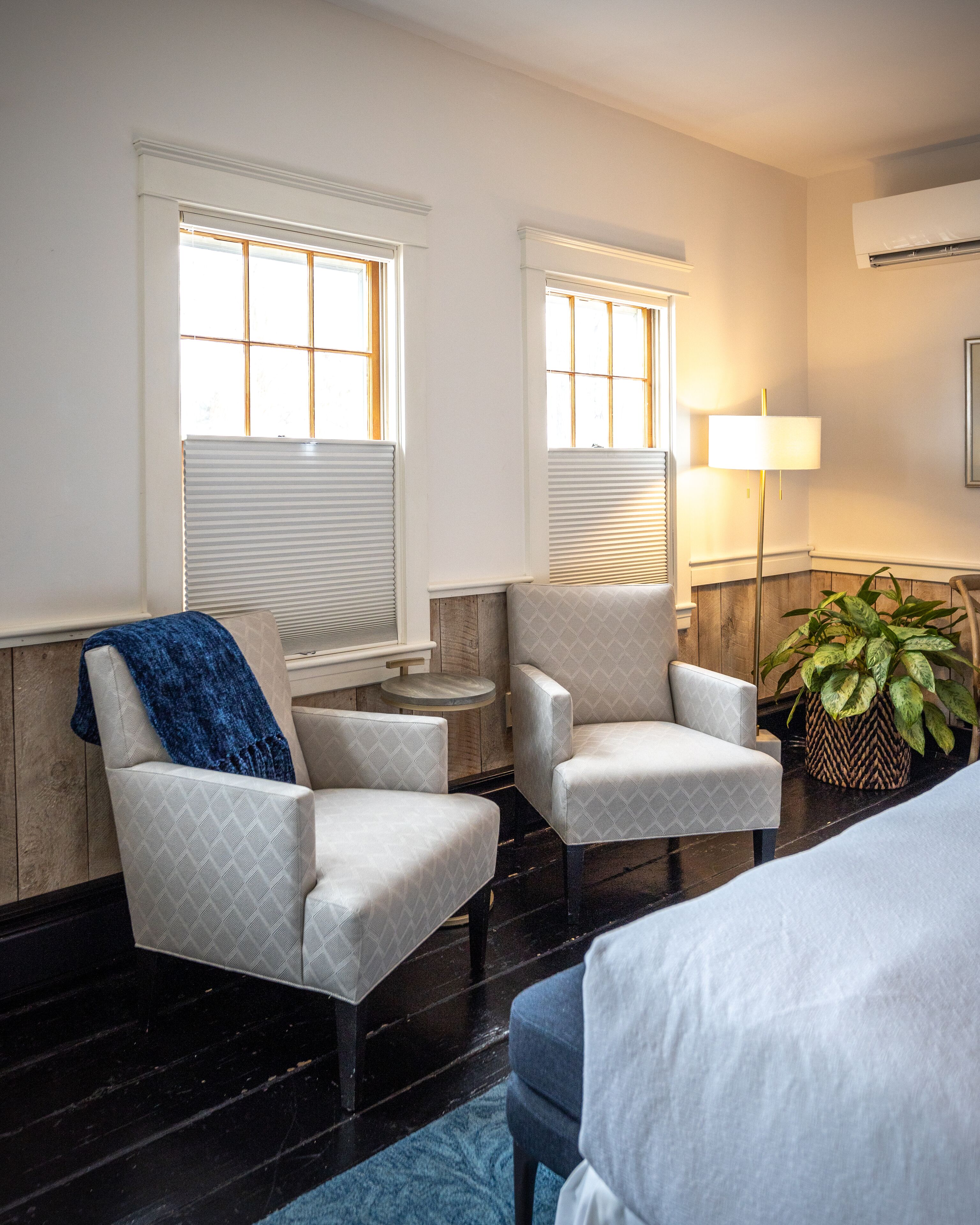 A room with two armchairs, a sofa, a lamp, and a potted plant.