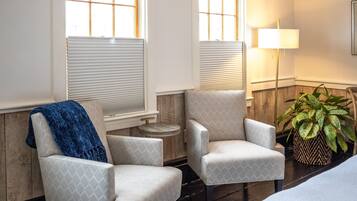 A room with two armchairs, a sofa, a lamp, and a potted plant.