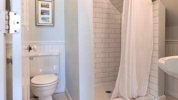 Ein Badezimmer mit Toilette, einem gerahmten Bild an der Wand und einer Dusche mit weißem Vorhang.