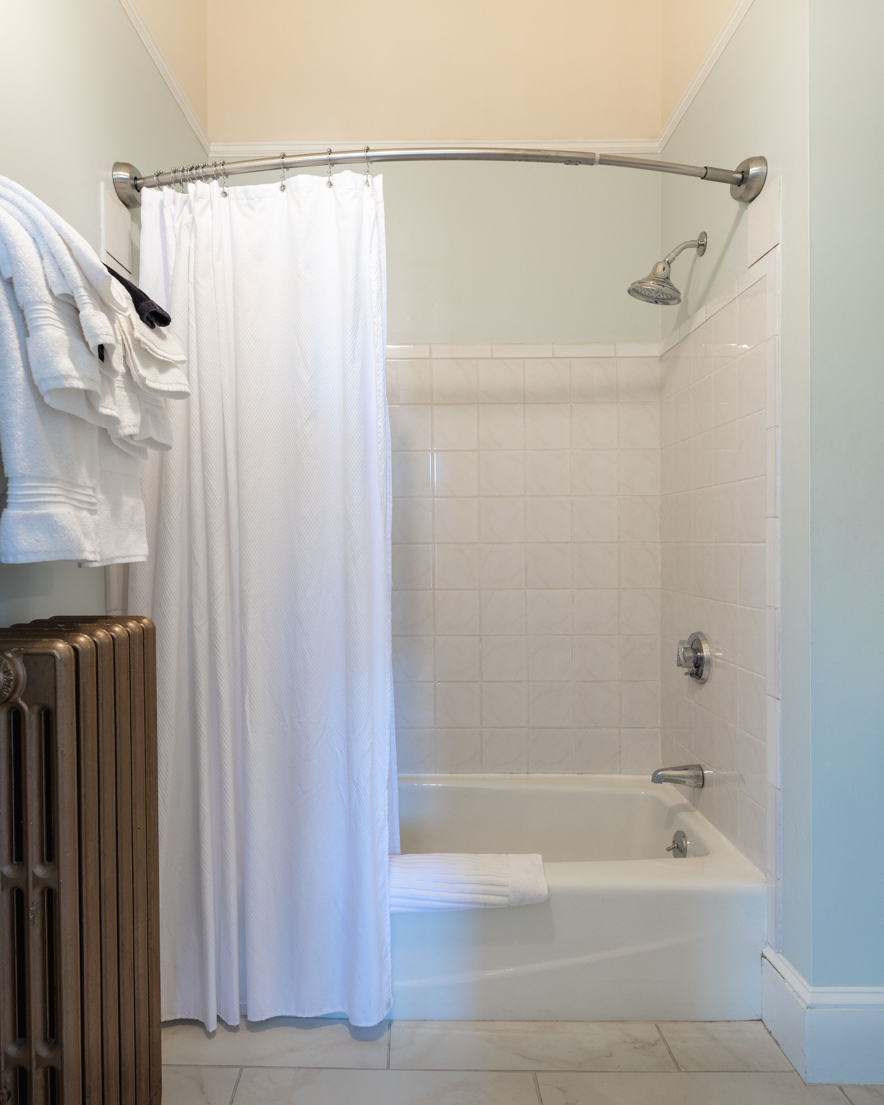 A bathroom with a shower, a bathtub, and a radiator.