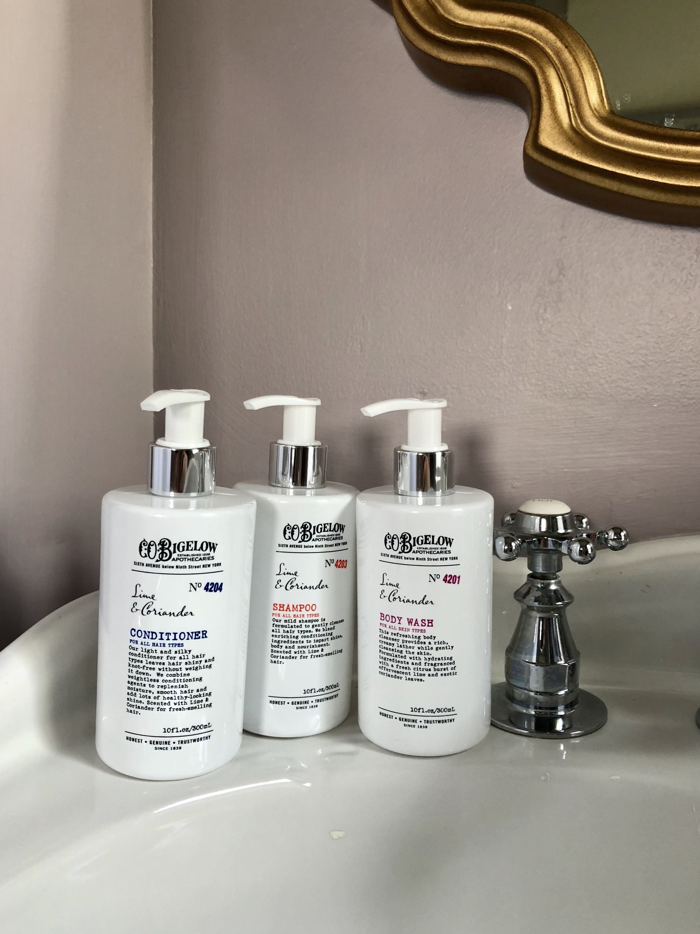 Three bottles of Bigelow conditioner and body wash on a bathroom sink.