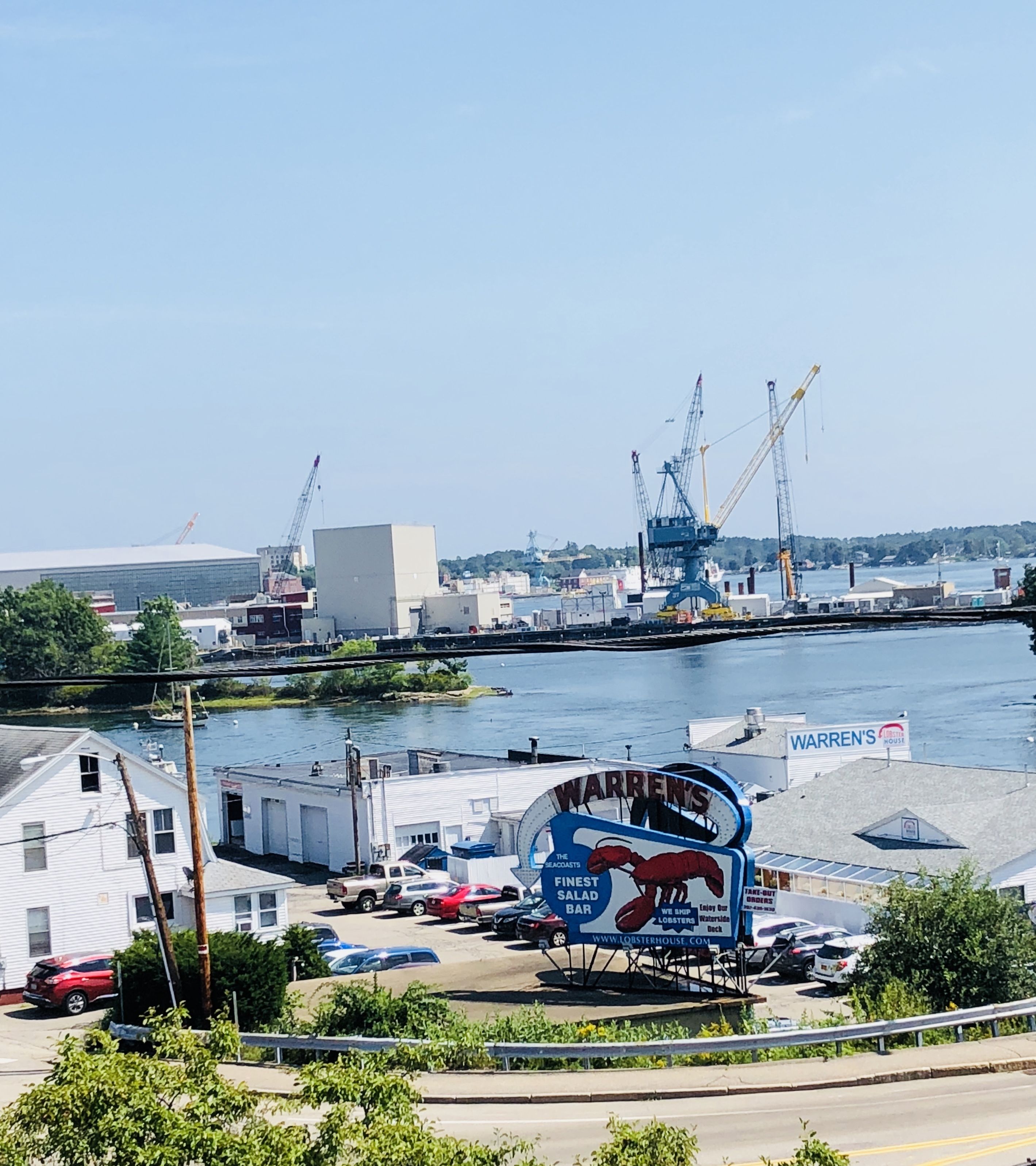 A waterfront view with a prominent lobster house sign, a crane, and a dock.