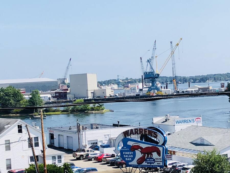 A waterfront view with a prominent lobster house sign, a crane, and a dock.