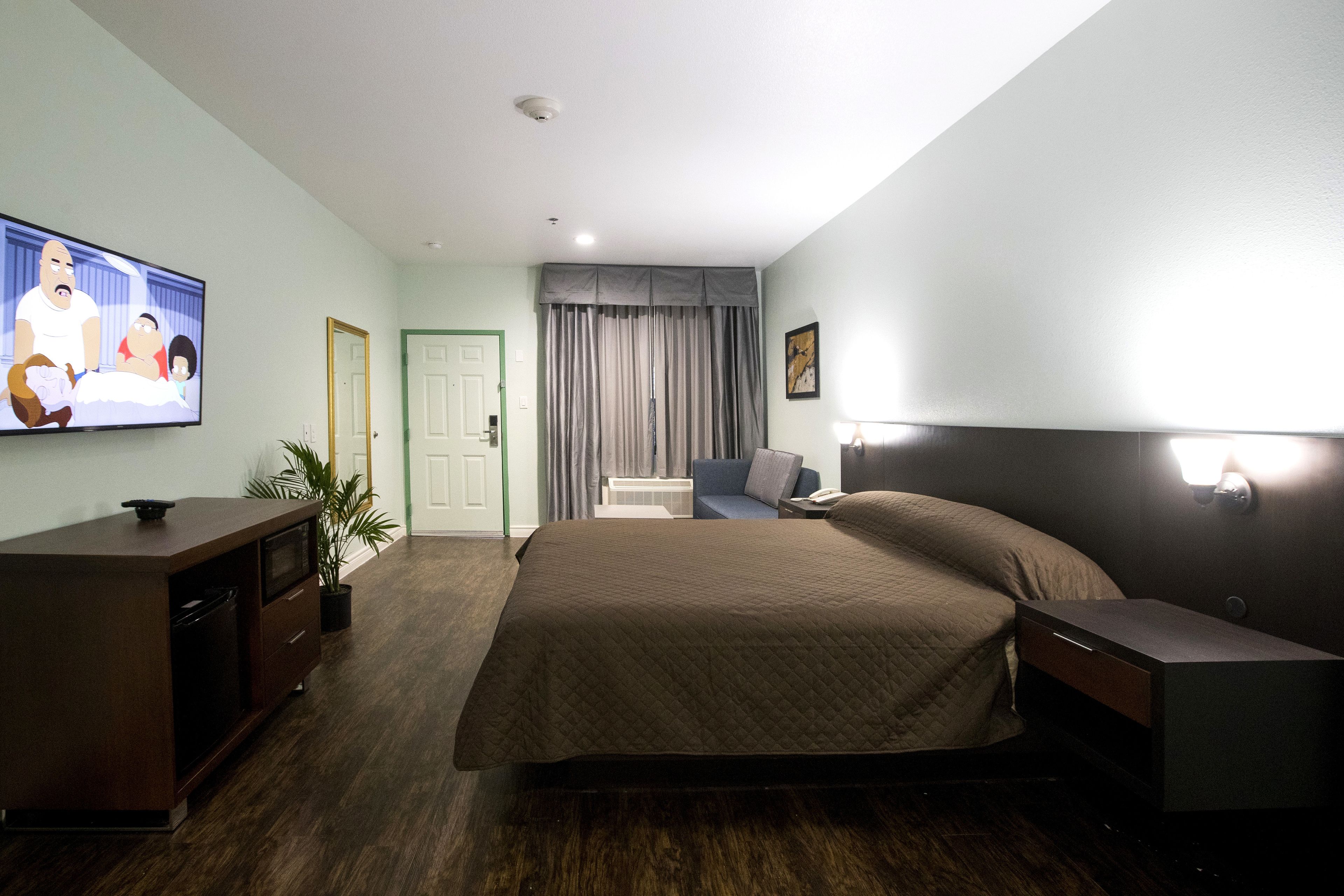 Una habitación de hotel con una cama grande, un televisor en la pared, un escritorio y una silla.