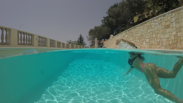 Une piscine à l’eau claire, avec des murs en pierre et une balustrade.