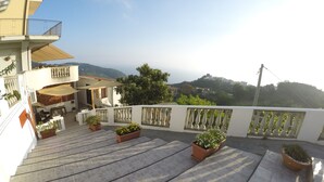 Une terrasse sur le toit agrémentée de plantes en pot, un espace repas et une vue sur le paysage environnant.