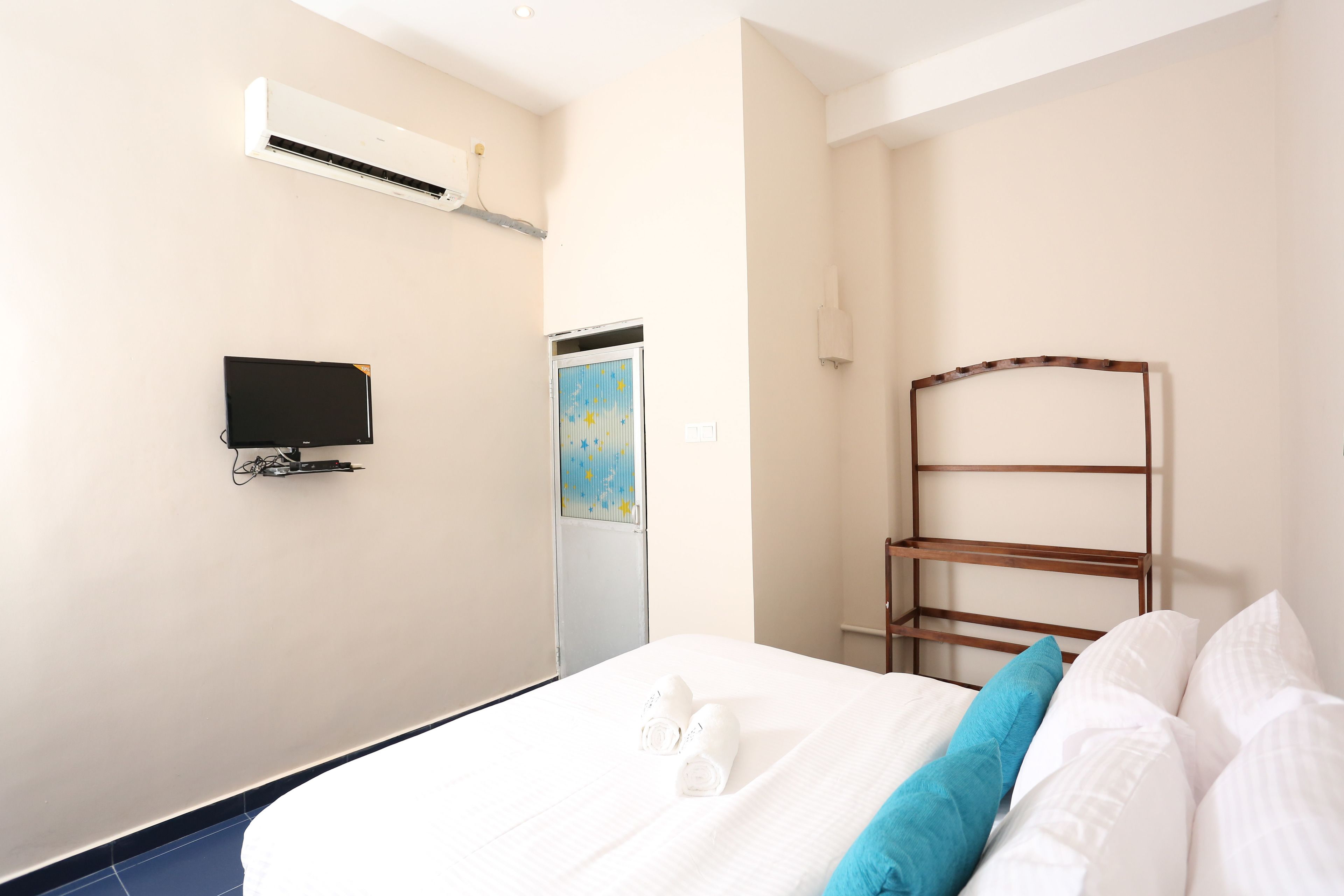 Una habitación de hotel con cama, televisión, aire acondicionado y ventana con vistas.