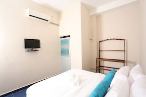 A hotel room with a bed, a TV, an air conditioner, and a window with a view. - Boots Travelers Lodge (Negombo)