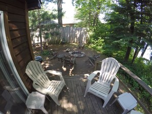 A wooden deck with Adirondack chairs and a small table, surrounded by a natural, wooded area. - Timber Bay Resort (Lac du Flambeau)