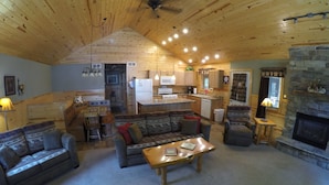 Interior acolhedor de uma cabana, com sala de estar, cozinha e área de jantar.