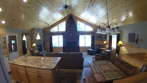 Um interior de cabana espaçoso, com uma cozinha grande, área de jantar e uma sala de estar acolhedora.