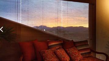 Una habitación con un amplio ventanal que da a un paisaje montañoso al atardecer.