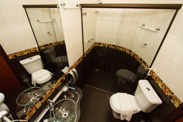 A bathroom with a glass shower enclosure, a toilet, and a bidet. - Estrada Real Palace Hotel (Brumadinho)