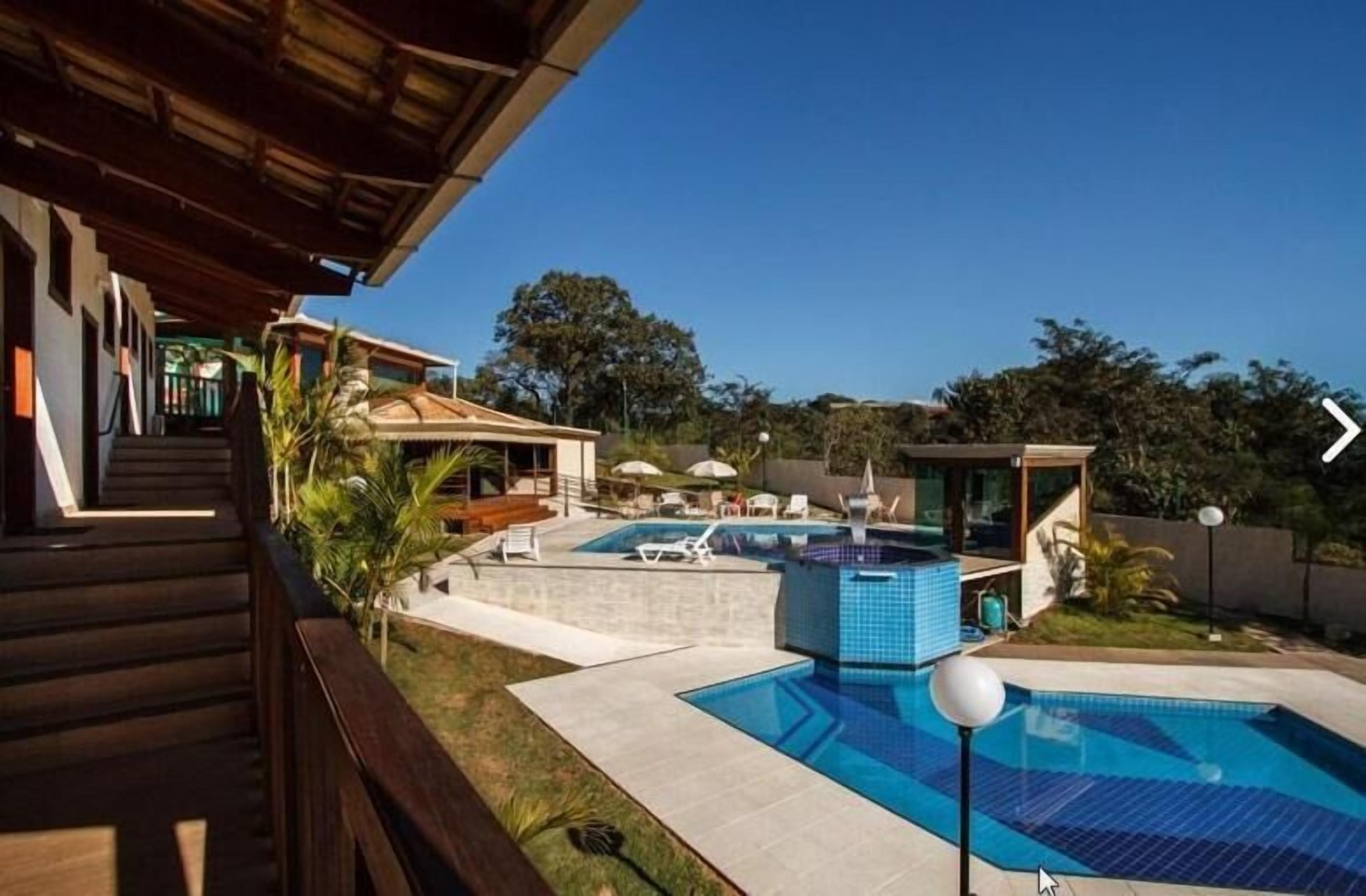 Uma área moderna de piscina ao ar livre com um deck de madeira, cadeiras de descanso e uma piscina pequena.