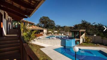 A modern outdoor swimming pool area with a wooden deck, lounge chairs, and a small pool.