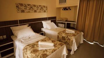Habitación de hotel con dos camas individuales, una mesita de noche, un escritorio, un espejo y un aire acondicionado de pared.