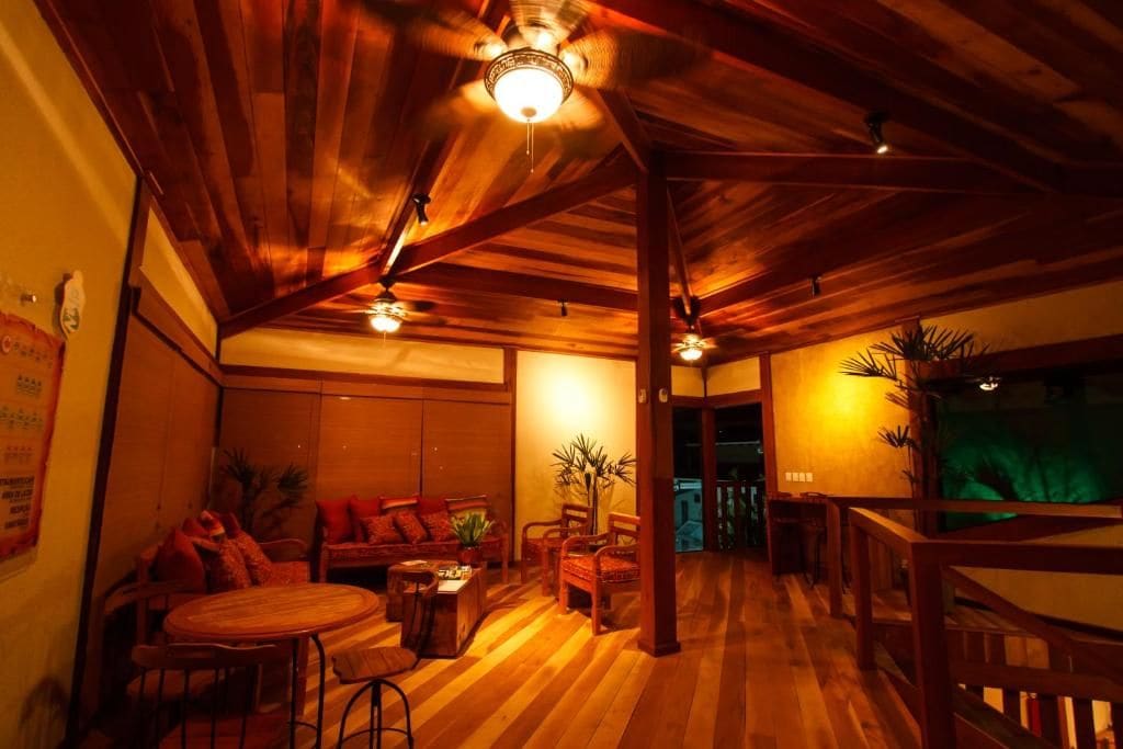 Una habitación con vigas de madera, ventilador de techo, sofá, mesa de comedor y sillas.