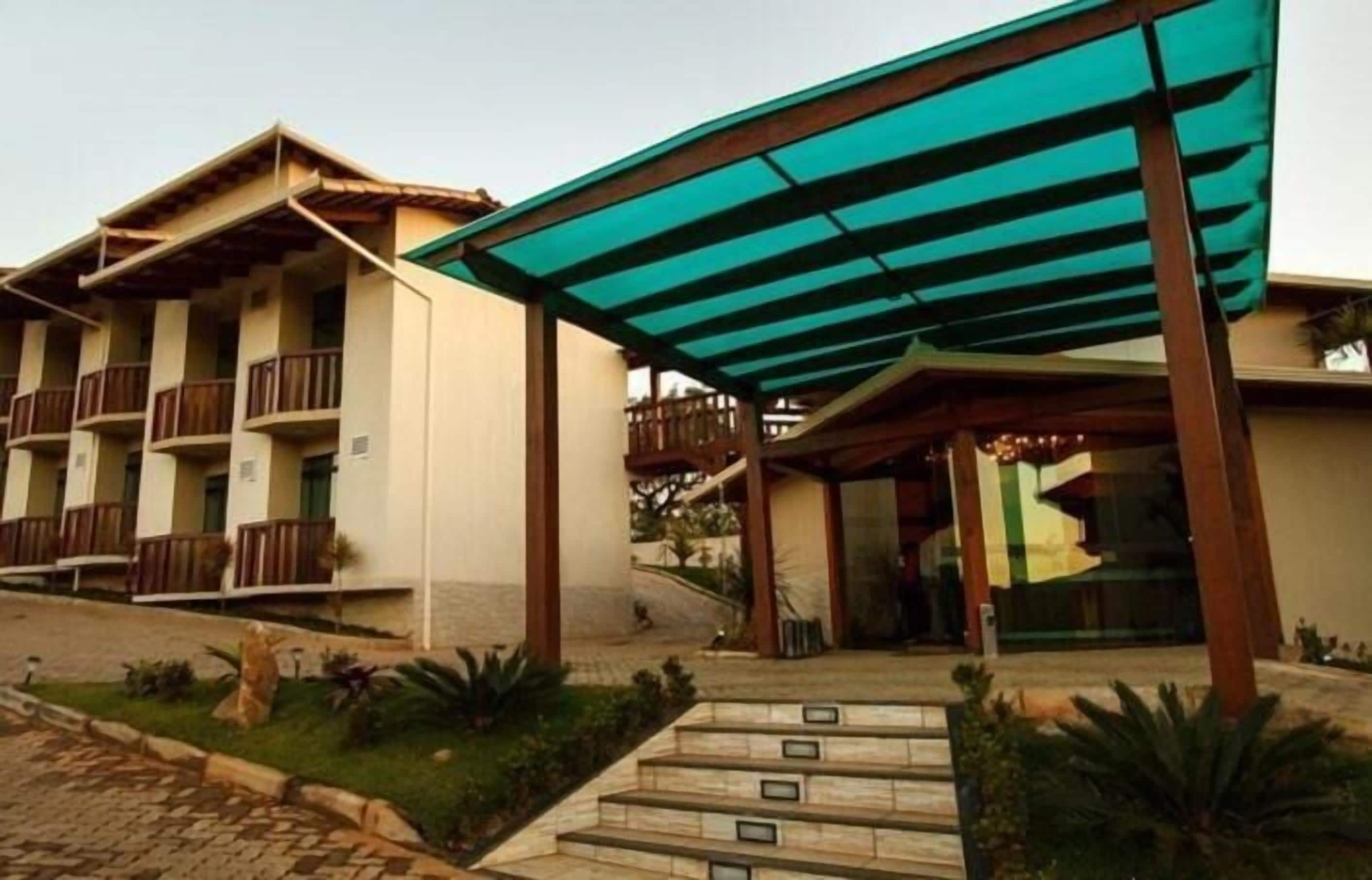 A hotel with a covered entrance, multiple balconies, and a landscaped entrance area.