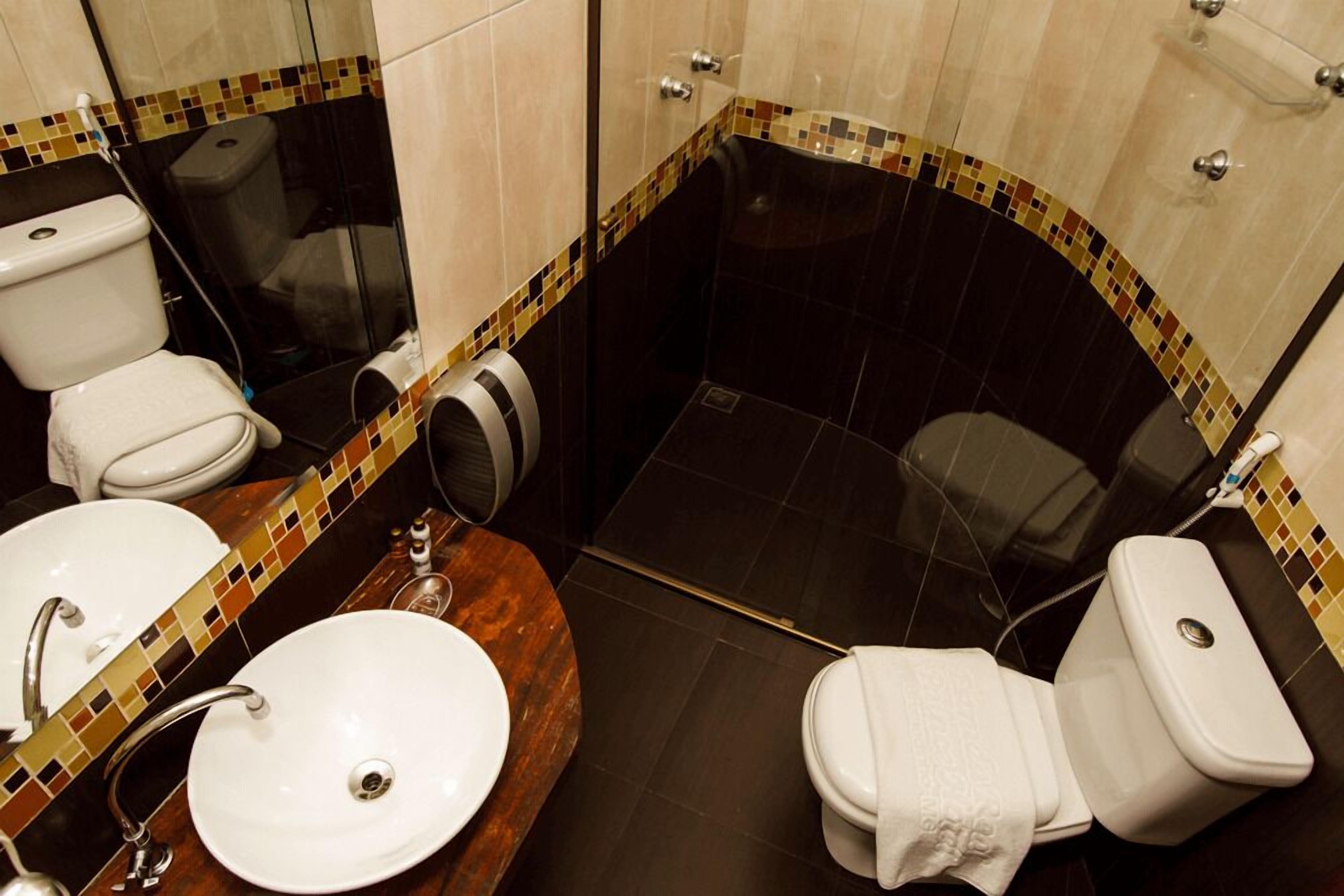 A bathroom with a white sink, two toilets, and a shower area.