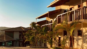 A multi-story building with balconies, surrounded by palm trees and a cobblestone pathway. - Estrada Real Palace Hotel (Brumadinho)