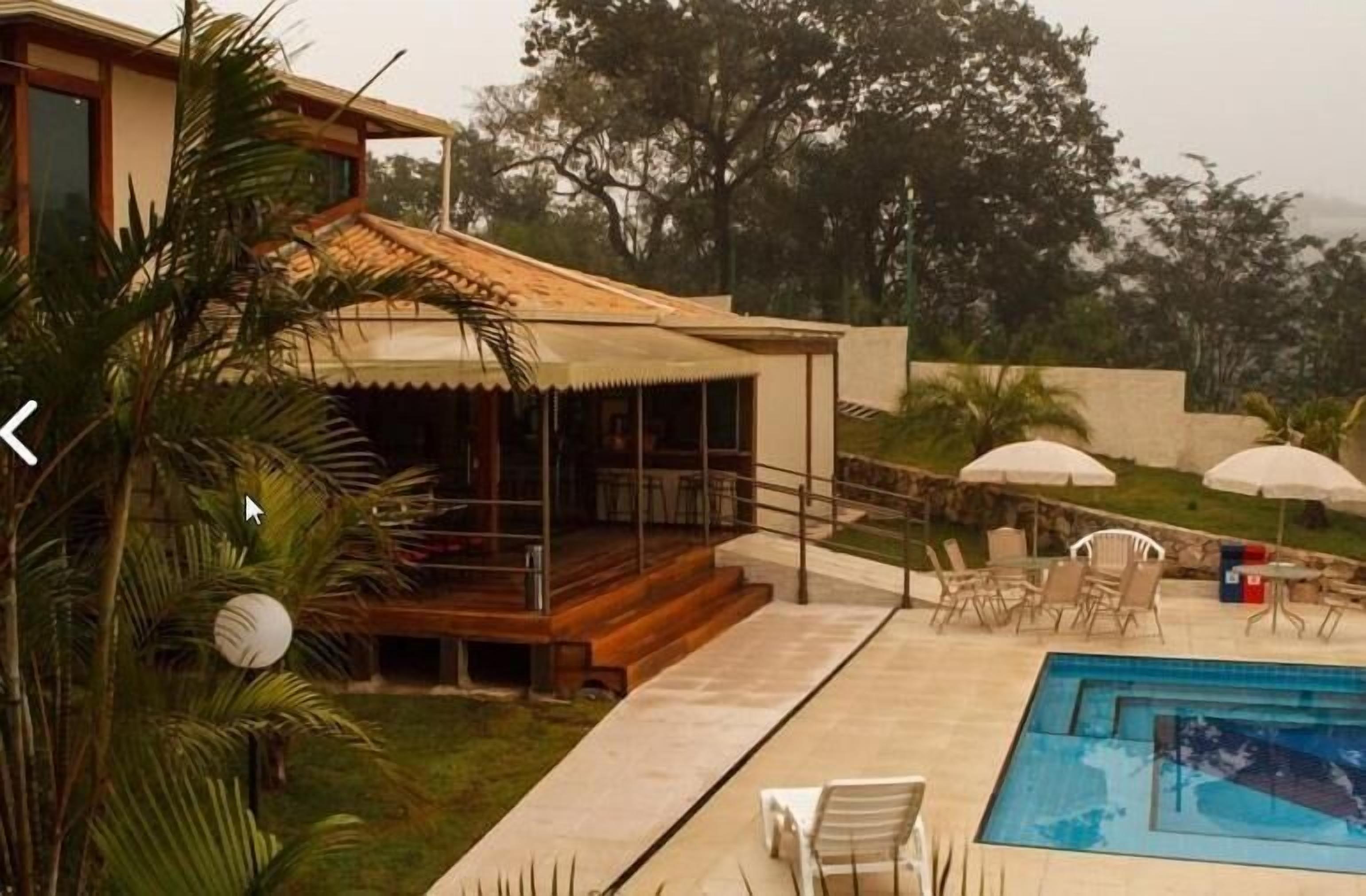 Zona junto a la piscina con un área de descanso cubierta, mobiliario exterior y una piscina.