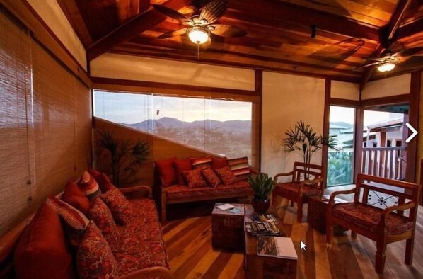 Una habitación acogedora con techo de madera, un conjunto de sofás, una mesita de centro y vistas a montañas a través de amplios ventanales.