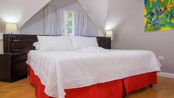 A bedroom with a bed, nightstands, a window with curtains, and a colorful painting on the wall.