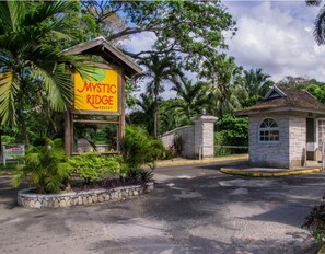 A sign for Mystic Ridge Resort surrounded by lush greenery and a stone building.