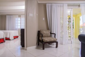 A hotel room with a bed, a chair, and a view of the outside.