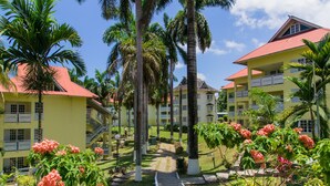A hotel with multiple yellow buildings, palm trees, and a pathway leading to the entrance.