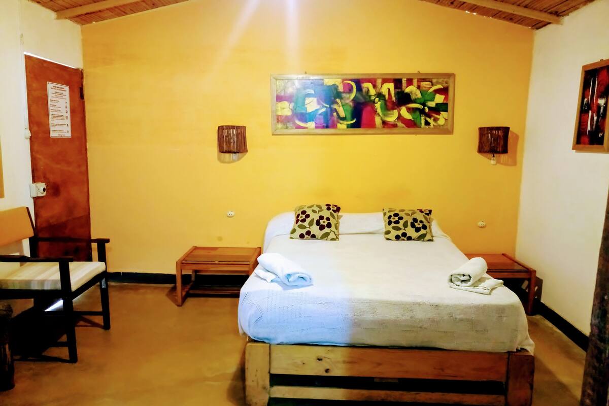 Une chambre avec un lit, deux tables de chevet, une chaise et un plafond en bois.