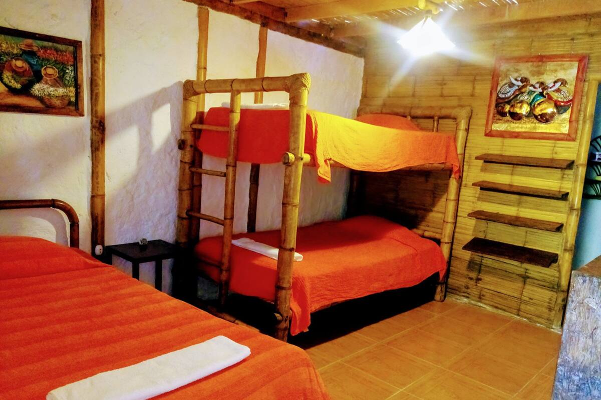 Une pièce avec deux lits superposés, une petite table et une étagère fixée au mur.
