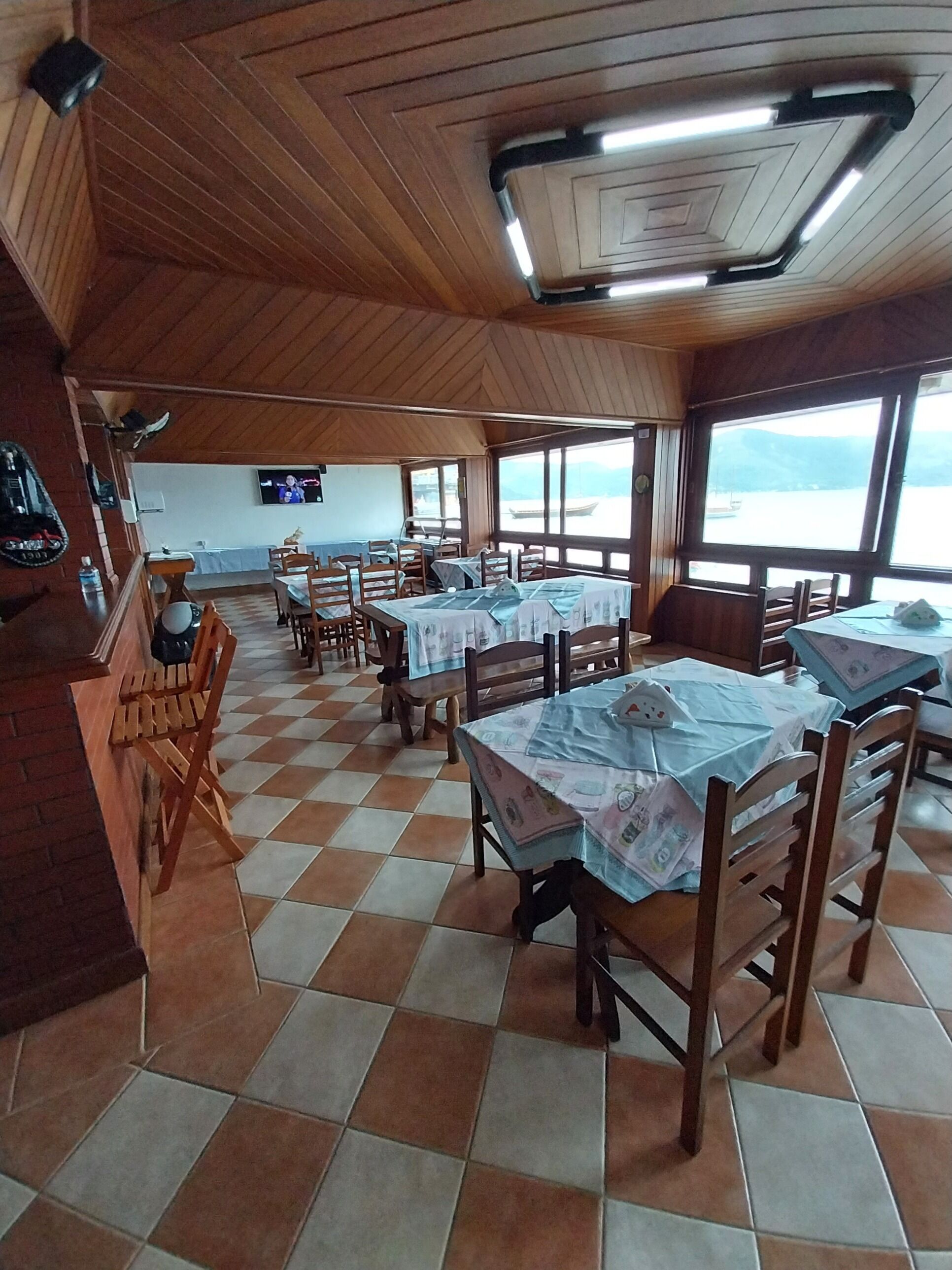 A restaurant with wooden interiors, tiled floors, and tables set for dining.