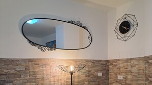 A room with two wicker chairs, a floor lamp, a wall clock, and a mirror with a geometric frame. - Vacanza a Casa (Rome)