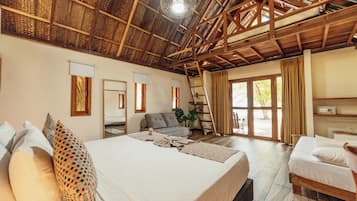 Una habitación amplia con una cama grande, una cama más pequeña, un sofá, una escalera y un ventanal.